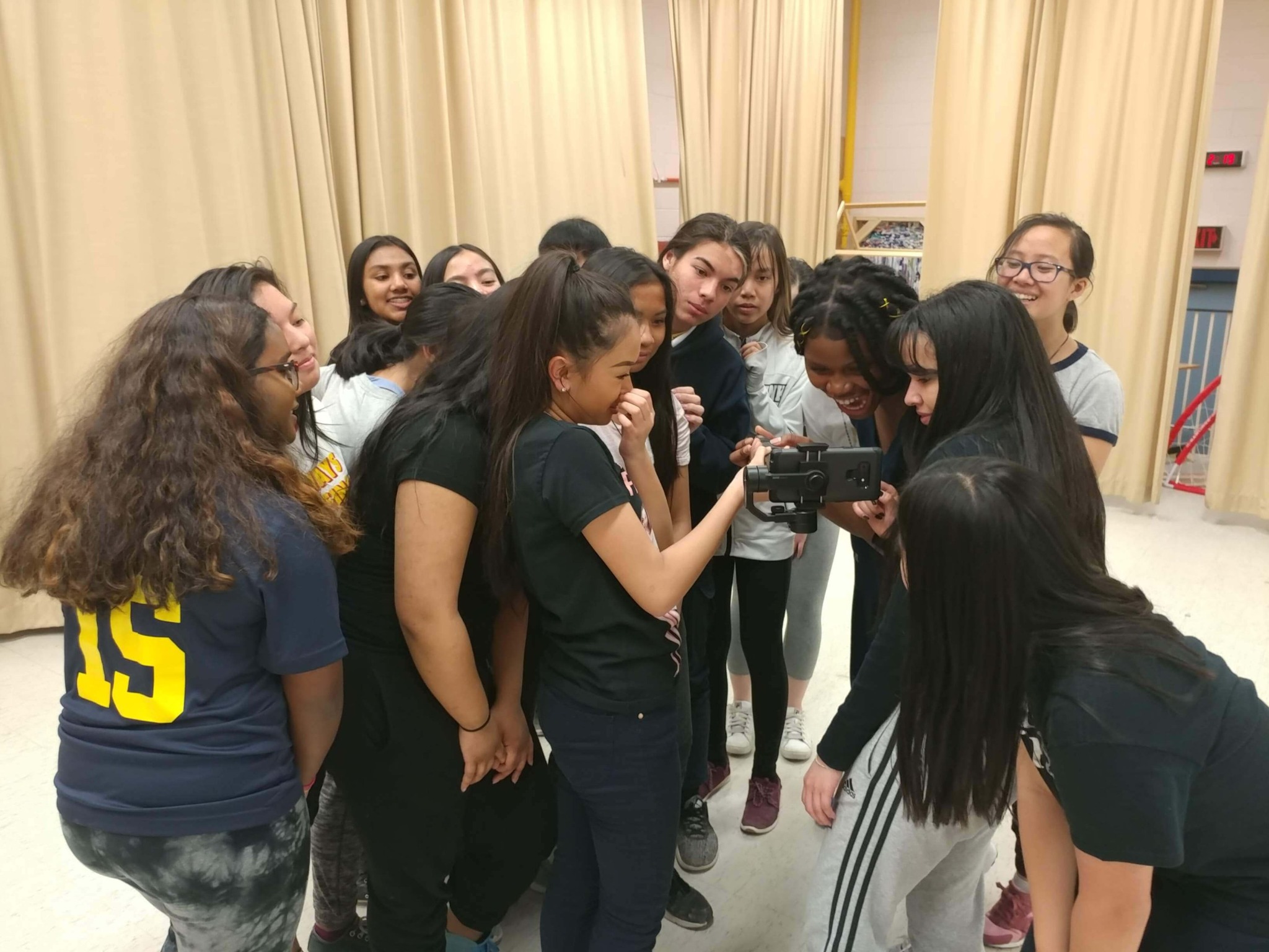 Students gathered around a phone while creating their introduction video